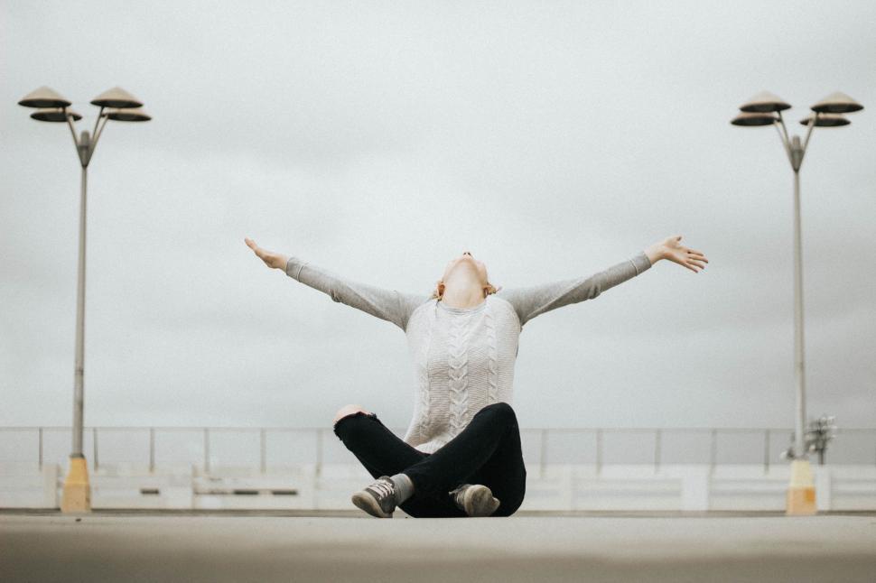 Free Image of Person Sitting on Ground With Arms Outstretched 