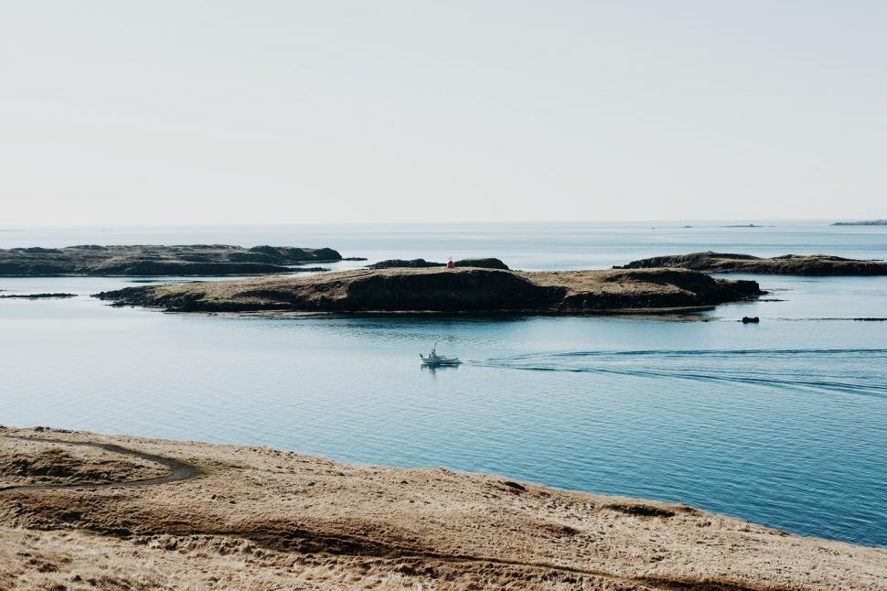 Free Image of Boat Sails Near Rocks on Water 