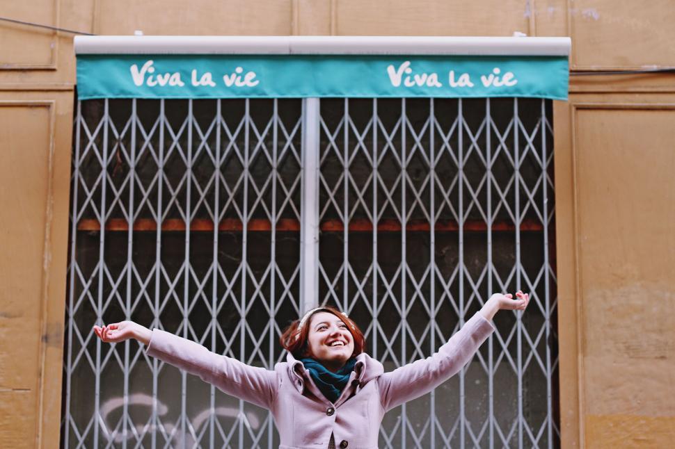 Free Image of Woman Standing in Front of Gate With Arms Outstretched 