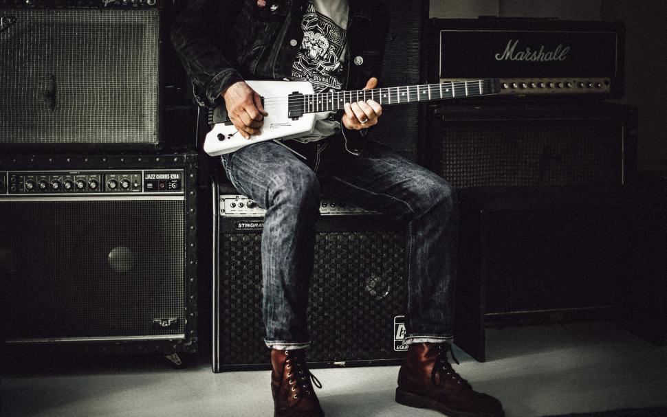 Free Image of Man Sitting on Top of a Chair Holding a Guitar 