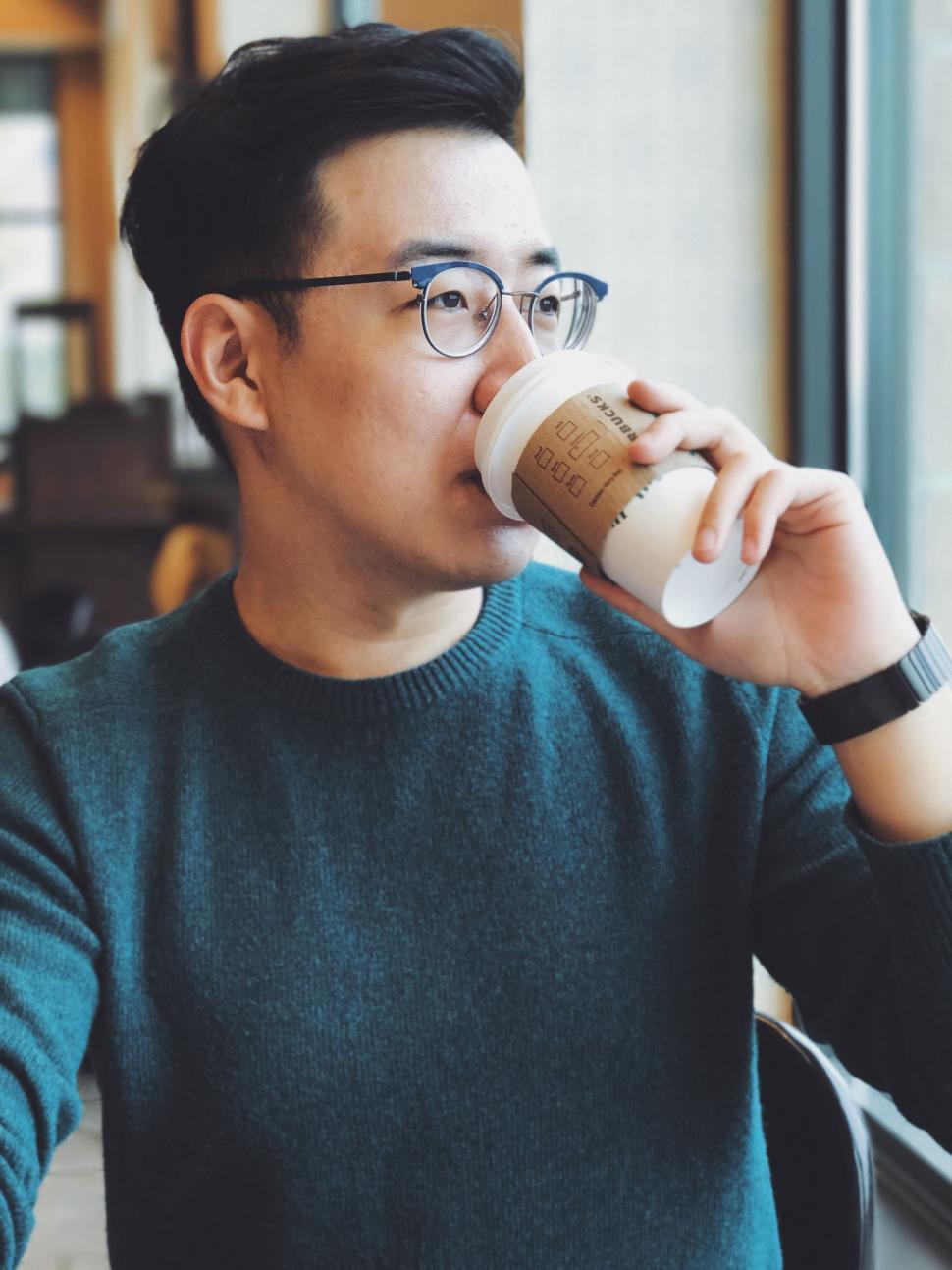 Free Image of Man Sitting at Table Drinking From Cup 