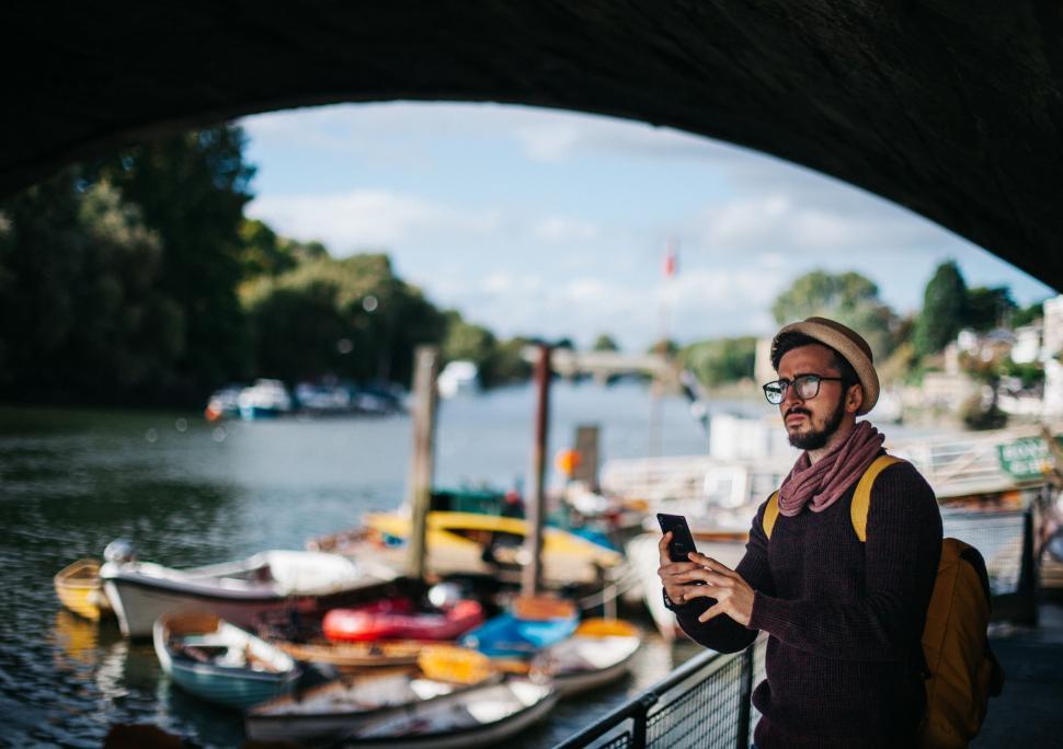 Free Image of Man Standing on Bridge Looking at Cell Phone 