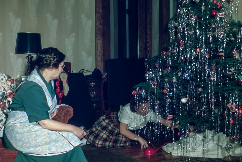 Free Image of Woman Sitting on Couch Next to Christmas Tree 