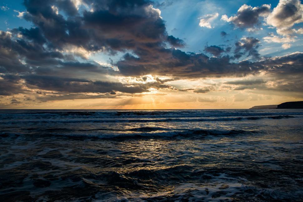 Free Image of Sun Shining Through Clouds Over Ocean 