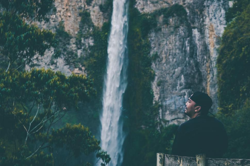 Free Image of Man Standing in Front of Waterfall 