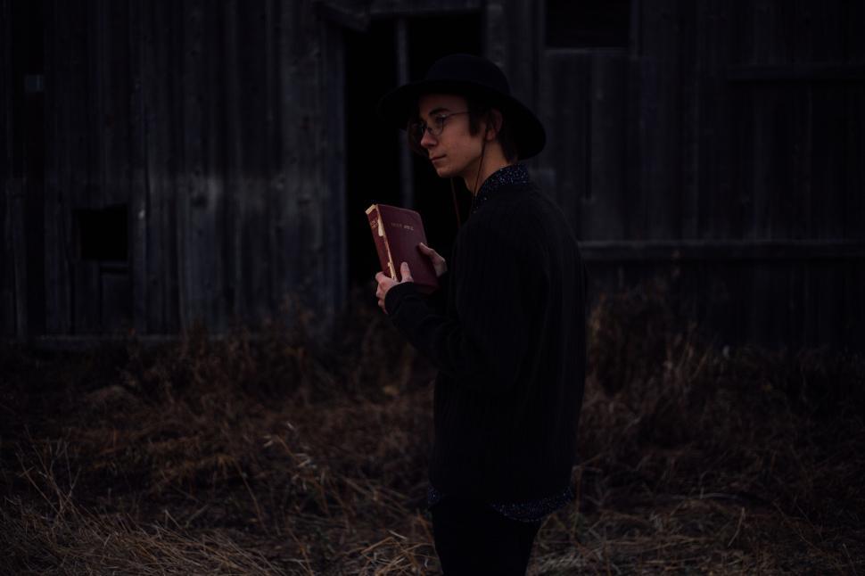 Free Image of Man Standing in the Dark Holding a Book 