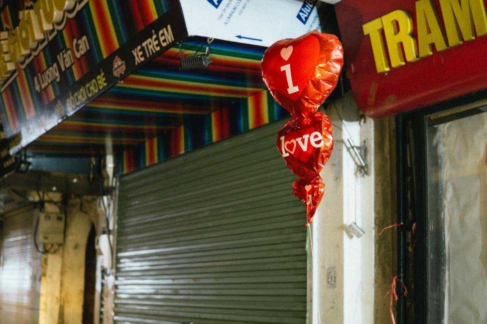 Free Image of Red Heart Shaped Balloon Hanging From the Side of a Building 