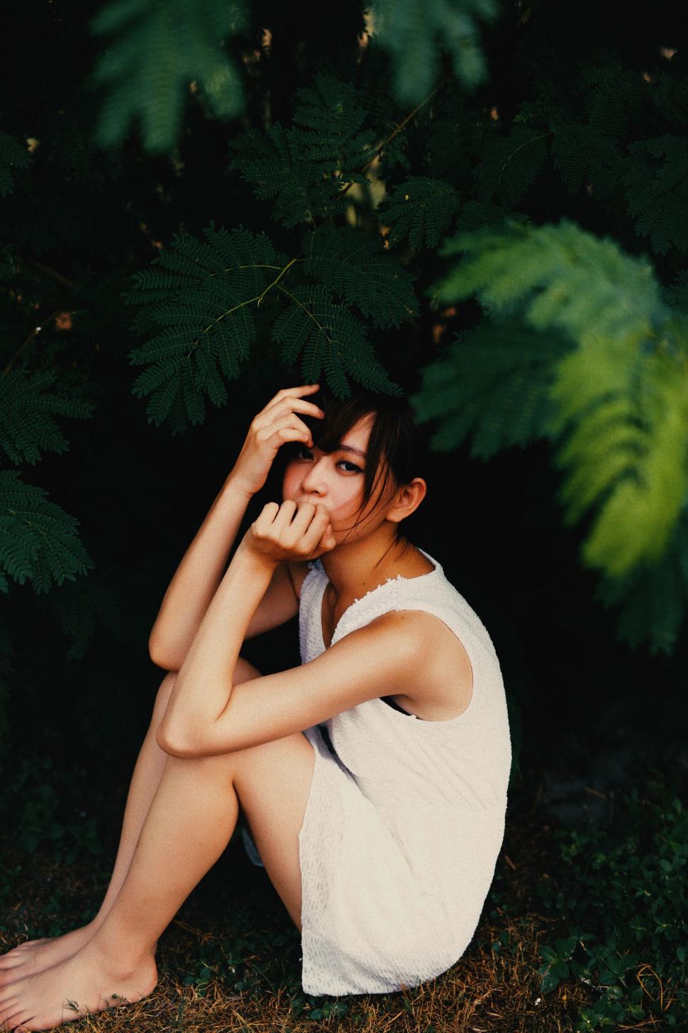 Free Image of Woman Sitting on Ground in Front of Tree 