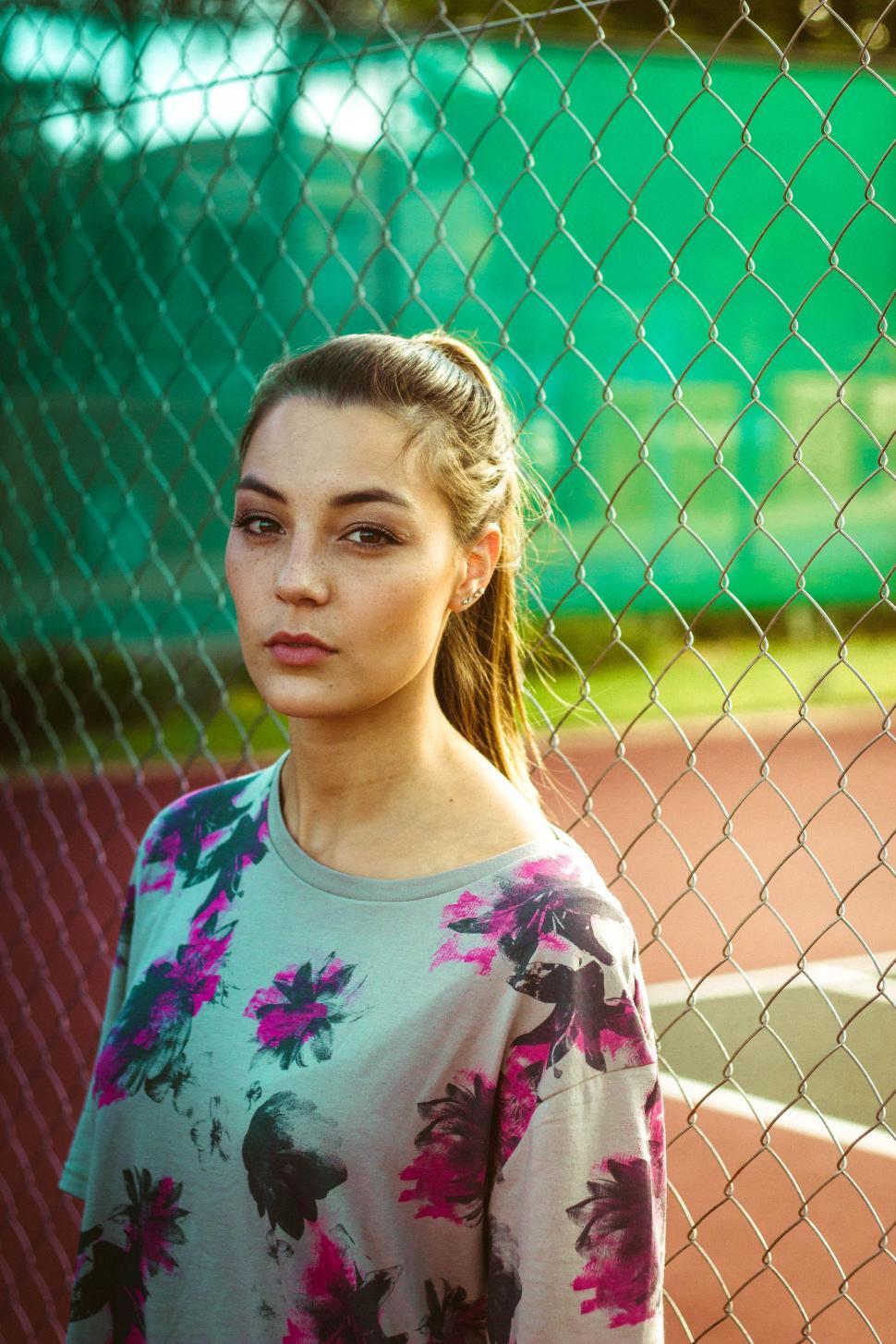 Free Image of Woman Standing in Front of Tennis Court 