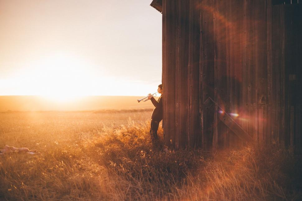 Free Image of Man Standing in Field Next to Tall Building 