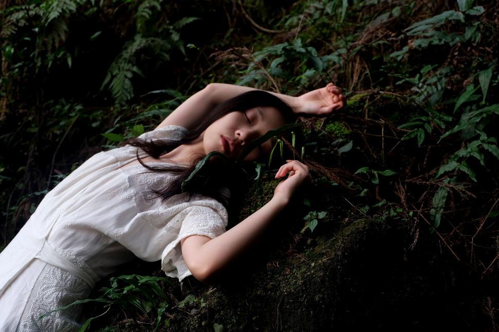 Free Image of Woman in White Dress Laying in Grass 