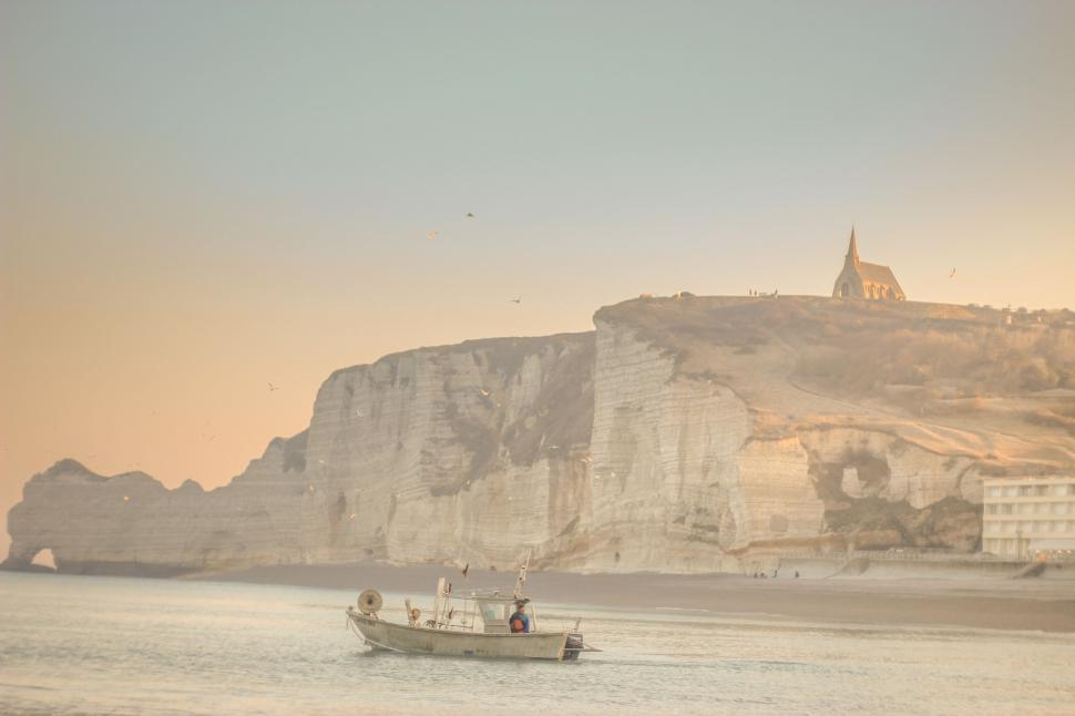 Free Image of Boat Sailing Near Cliff on Water 