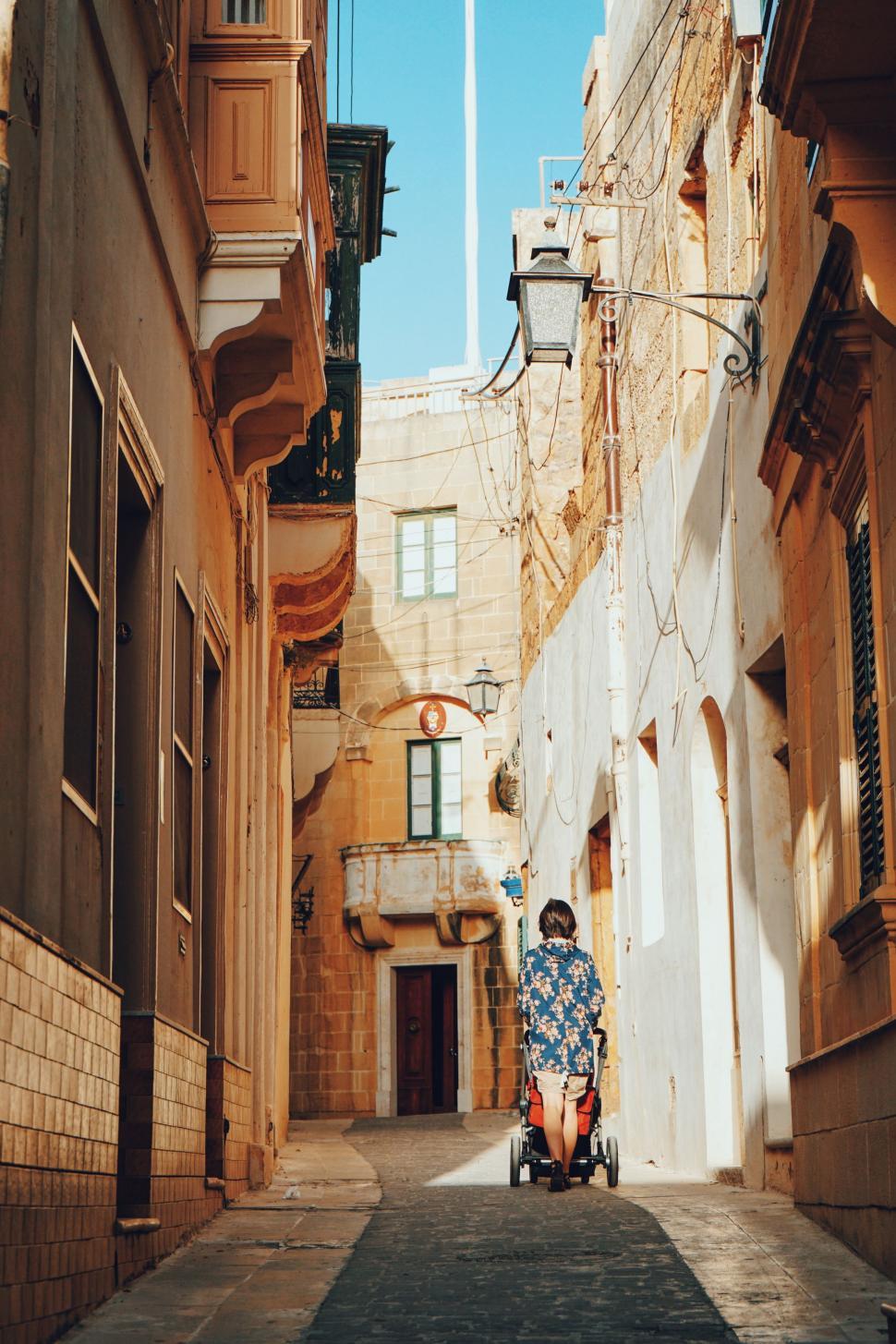 Free Image of Person Riding Scooter Down Narrow Street 