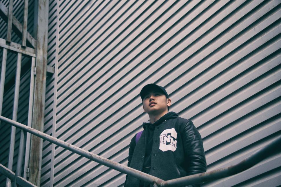 Free Image of Man in Black Jacket Standing on Metal Hand Rail 