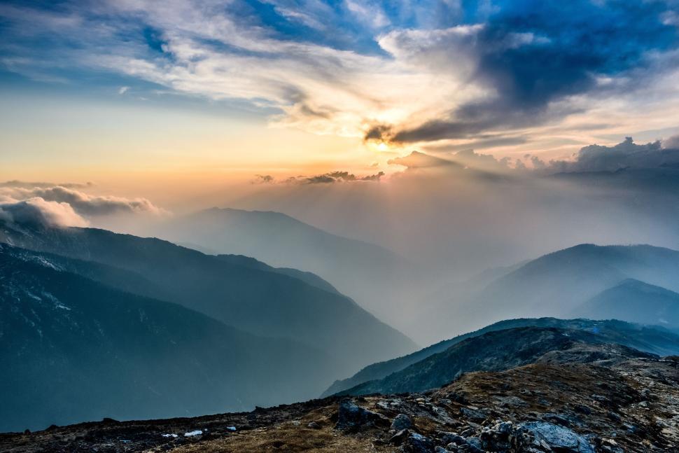 Free Image of Sun Shining Through Clouds Over Mountains 
