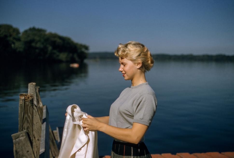 Free Image of Woman Standing on Dock Beside Body of Water 