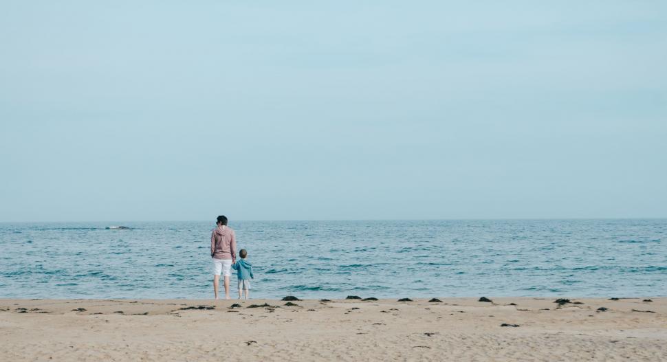 Free Image of Man Standing on Sandy Beach Next to Ocean 