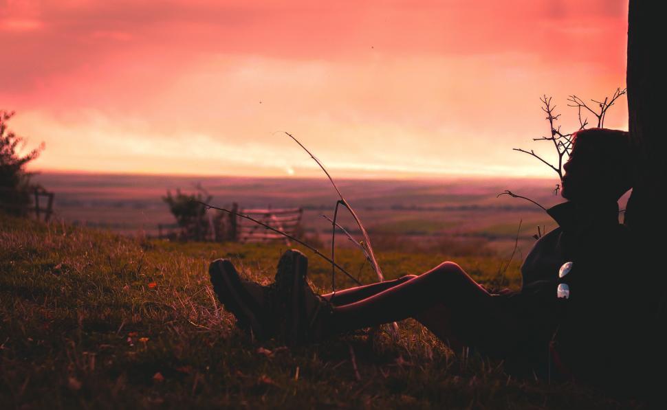 Free Image of Person Sitting in Grass Under Cloudy Sky 
