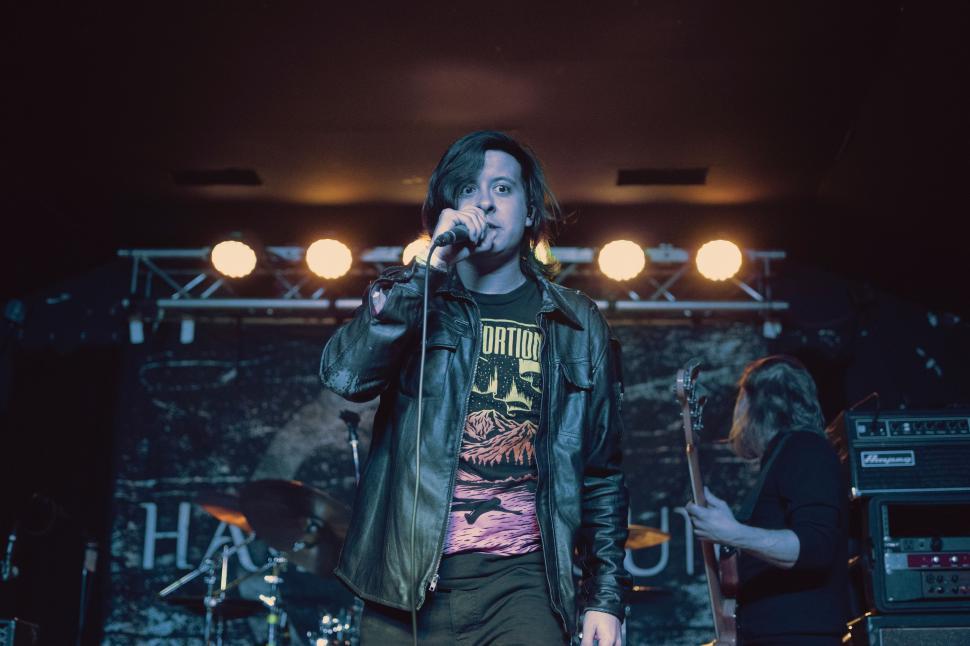 Free Image of Man Standing on Stage Holding Microphone 
