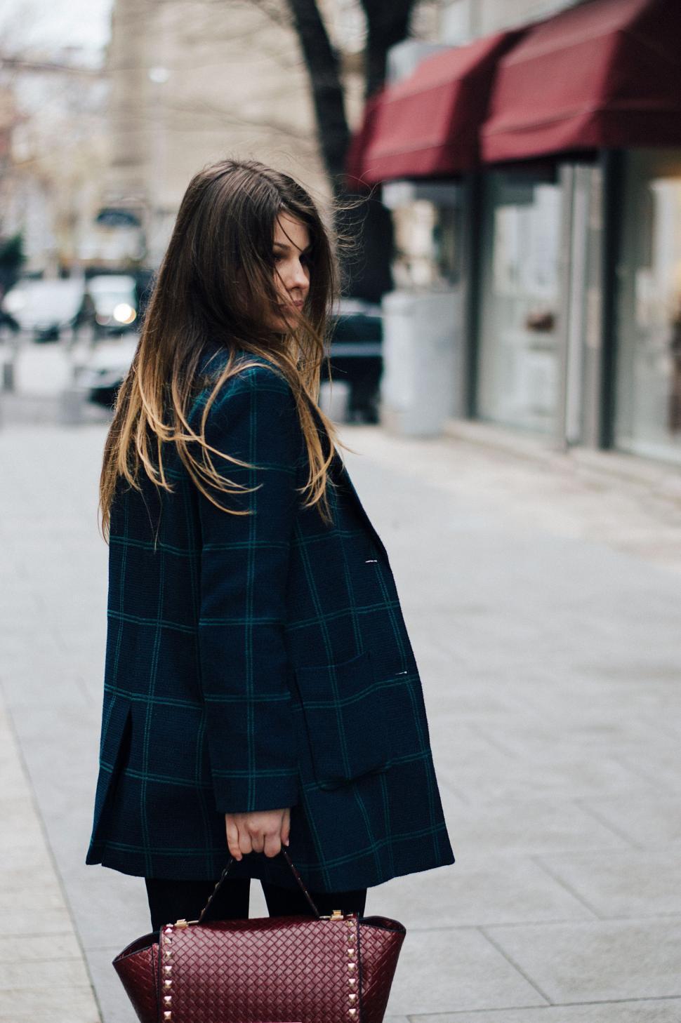Free Image of Woman Standing on Sidewalk With Handbag 