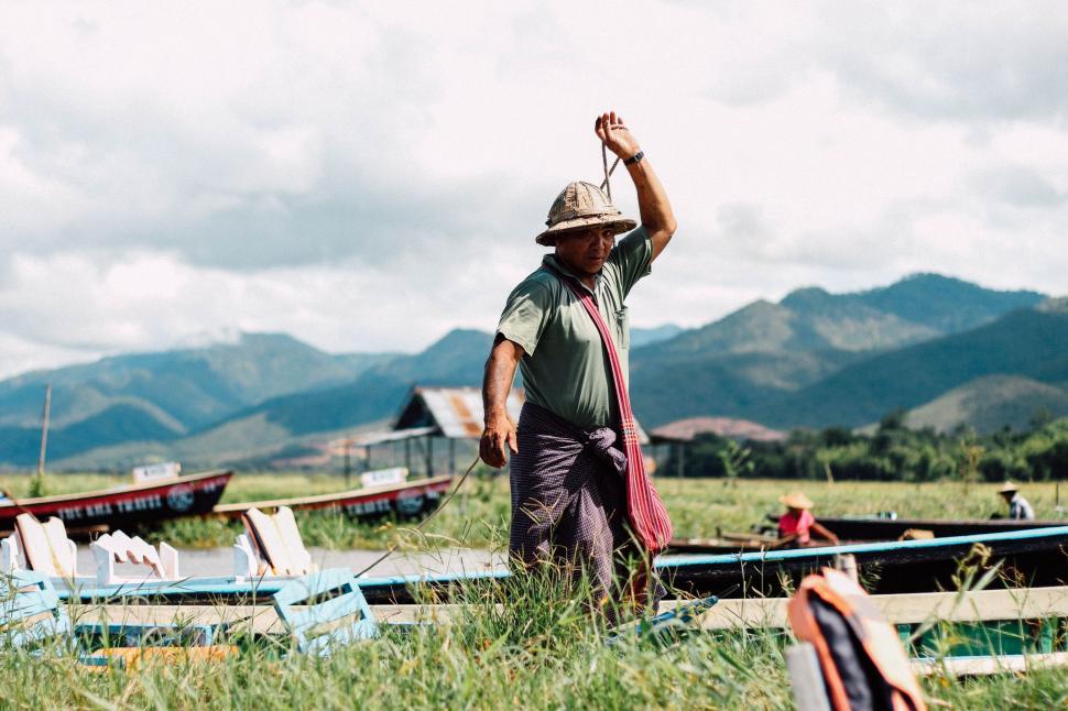 Free Image of Man Standing in Field Next to Boats 
