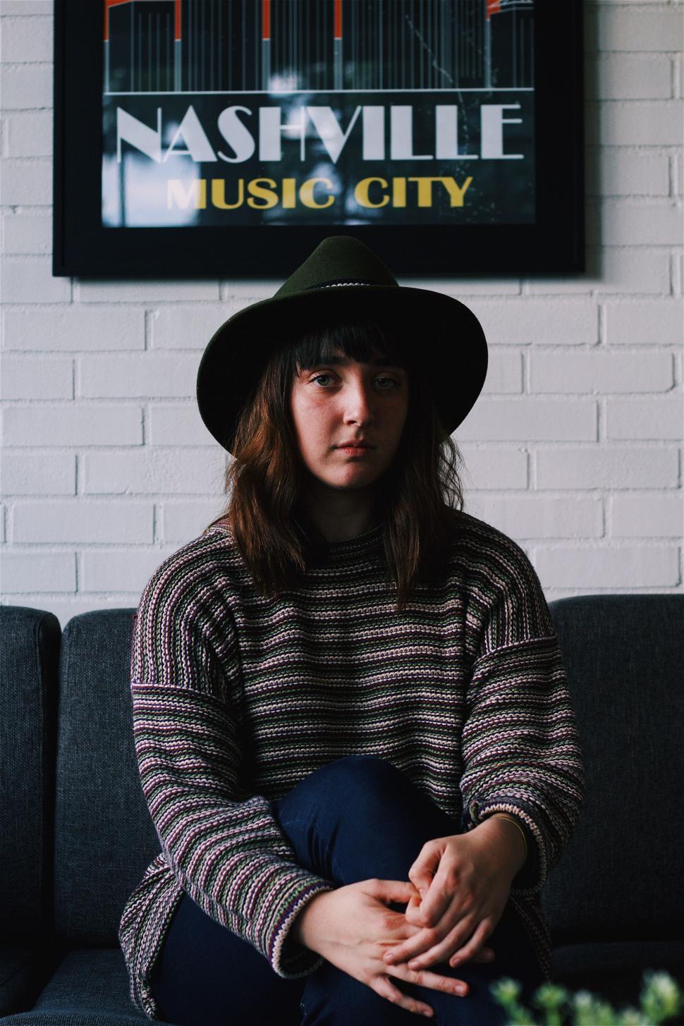 Free Image of Person Sitting on Couch Wearing Hat 