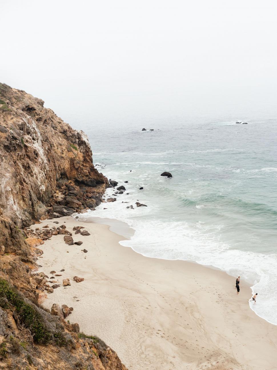Free Image of Couple Standing on Cliff Overlooking Ocean 