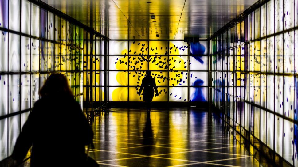 Free Image of Person Walking Down a Hallway With a Large Window 