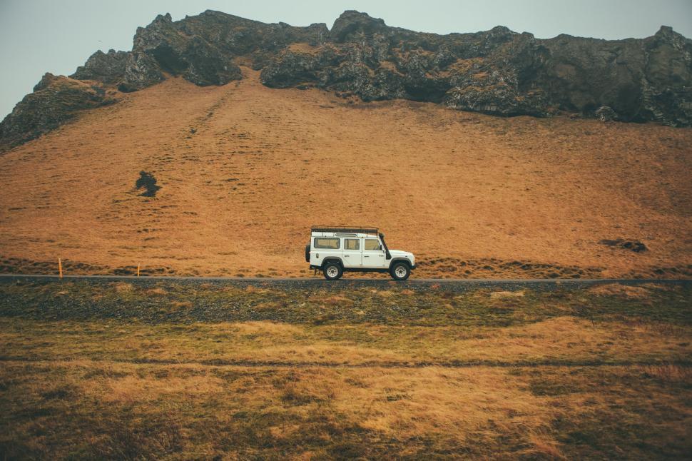 Free Image of White Truck Driving Down Road Next to Mountain 