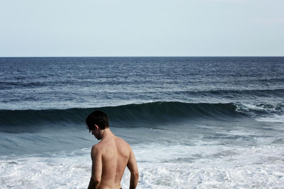 Free Image of Man Standing on Beach Next to Ocean 