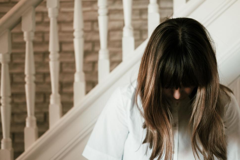 Free Image of Woman With Long Hair Standing in Front of a Staircase 