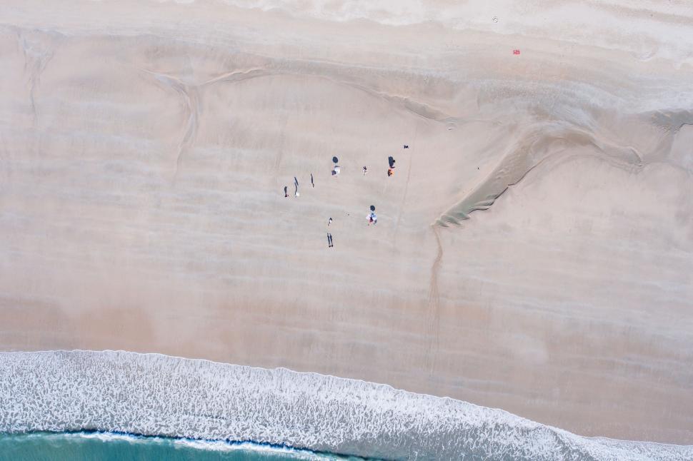 Free Image of Group of People Standing on Sandy Beach 