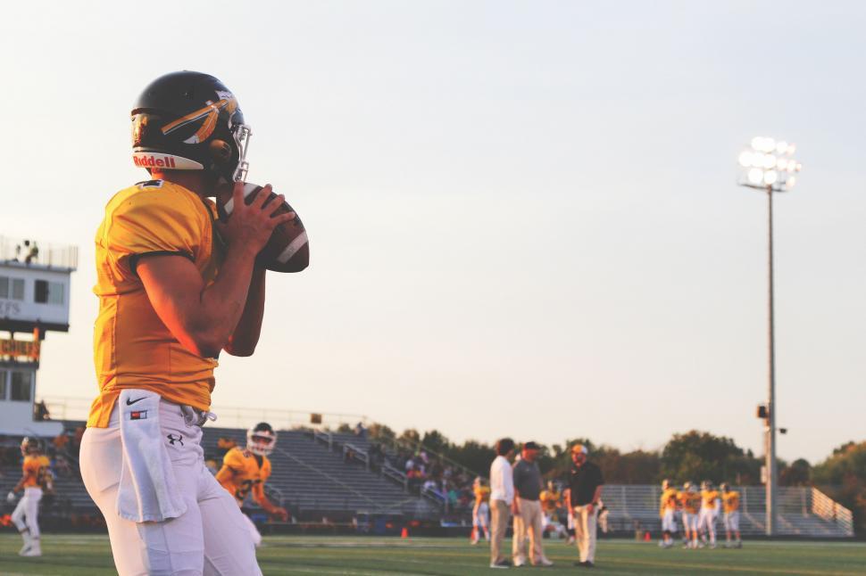 Free Image of Football Player Holding a Football on a Field 