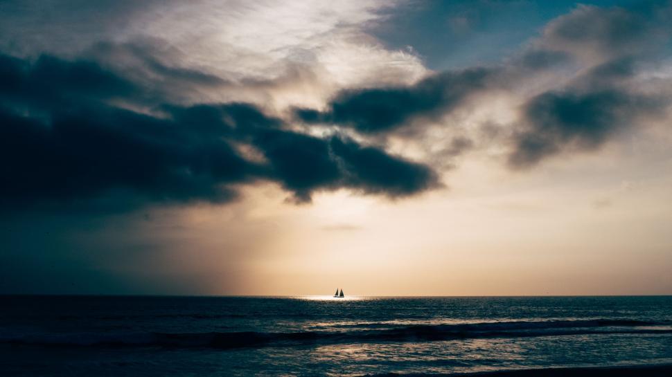 Free Image of Sun Shining Through Clouds Over Ocean 