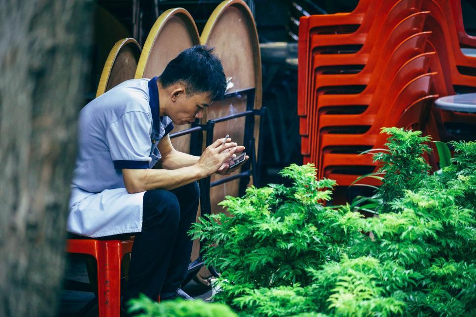 Free Image of Man Sitting on Red Chair Next to Plants 