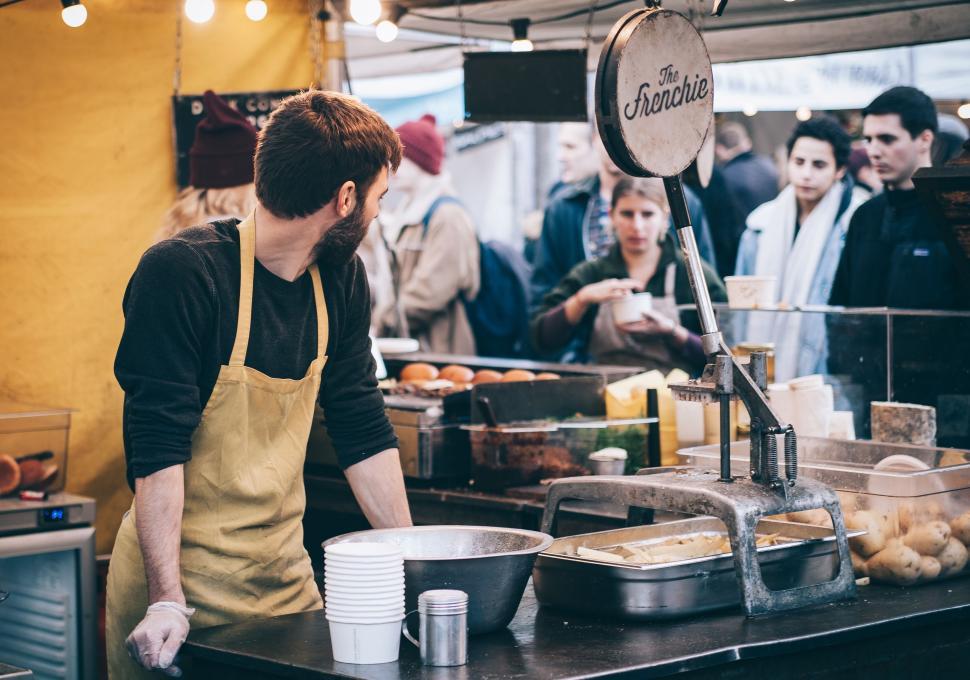 Free Image of Group of People Standing Around Food Stand 