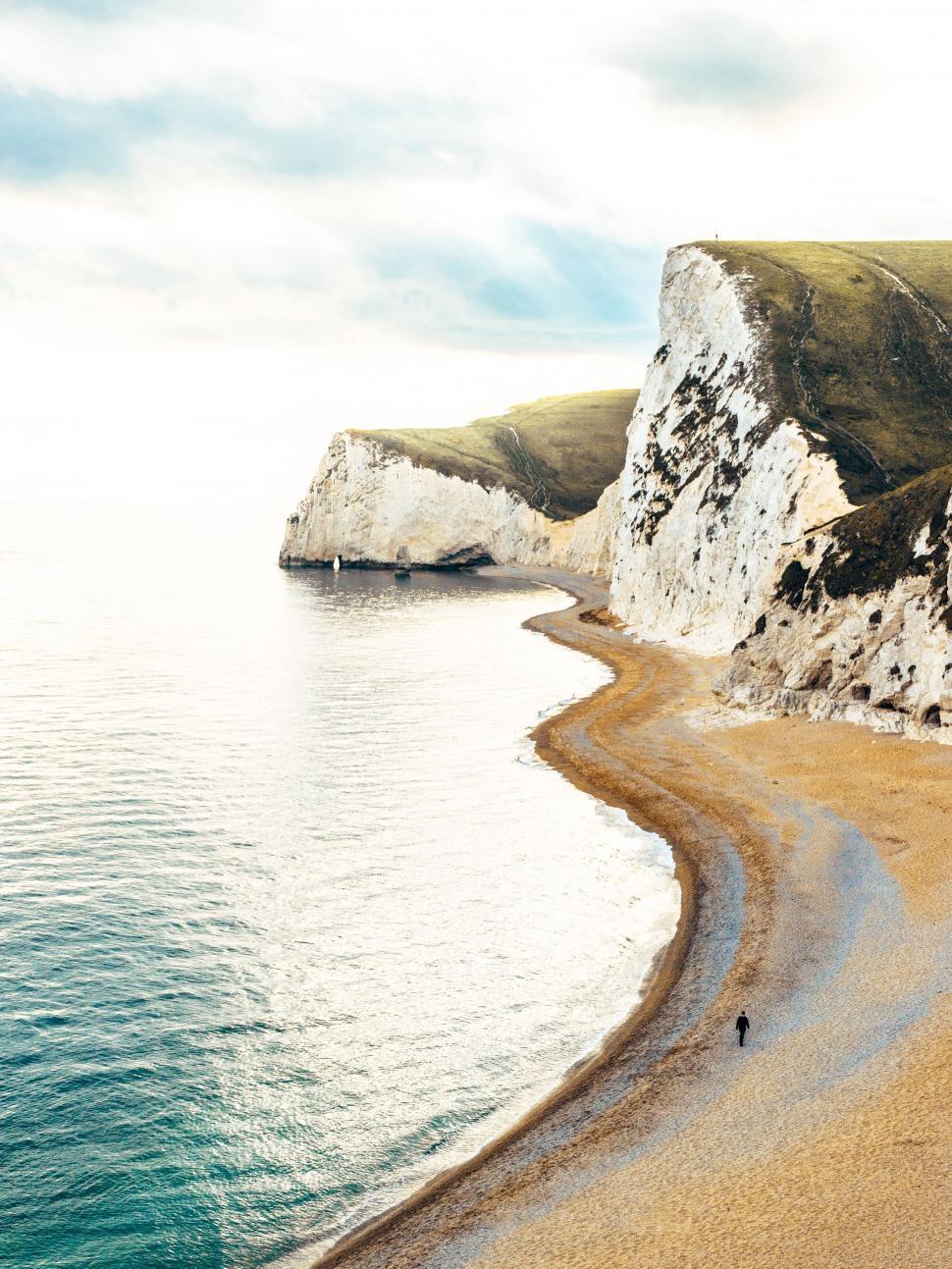 Free Image of Person Walking on Beach Next to Ocean 