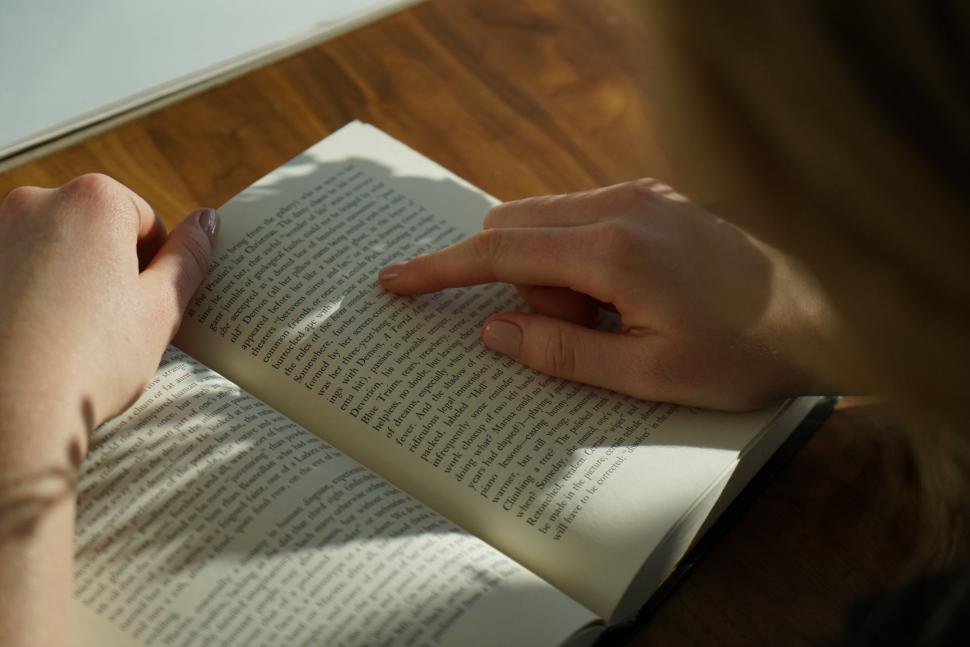 Free Image of Person Reading a Book on a Wooden Floor 