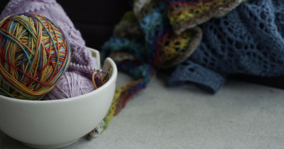 Free Image of White Bowl of Yarn With Pile of Blankets 
