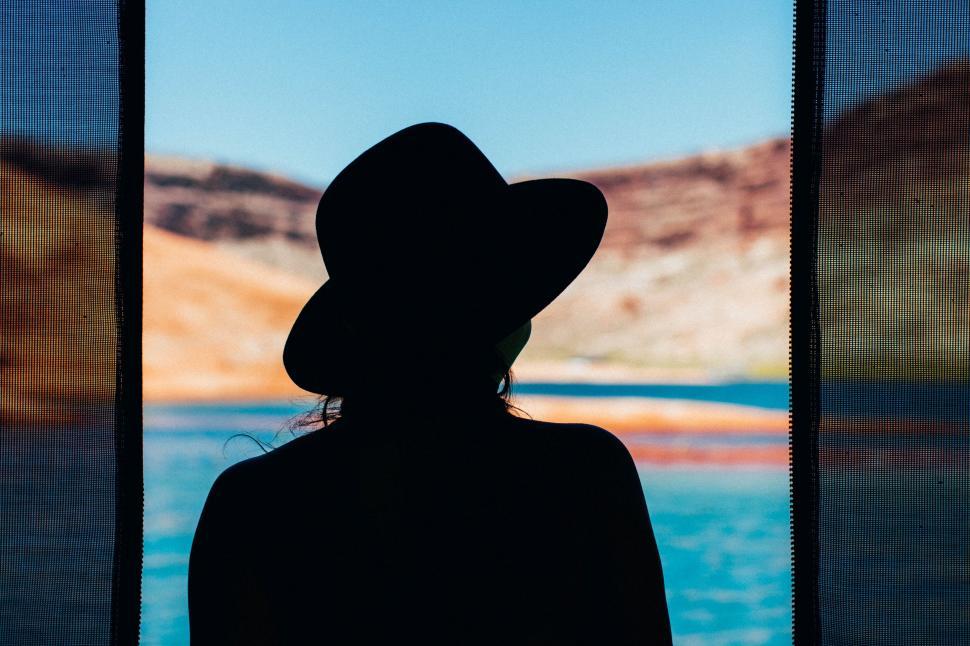 Free Image of Person With Hat Looking Out a Window 