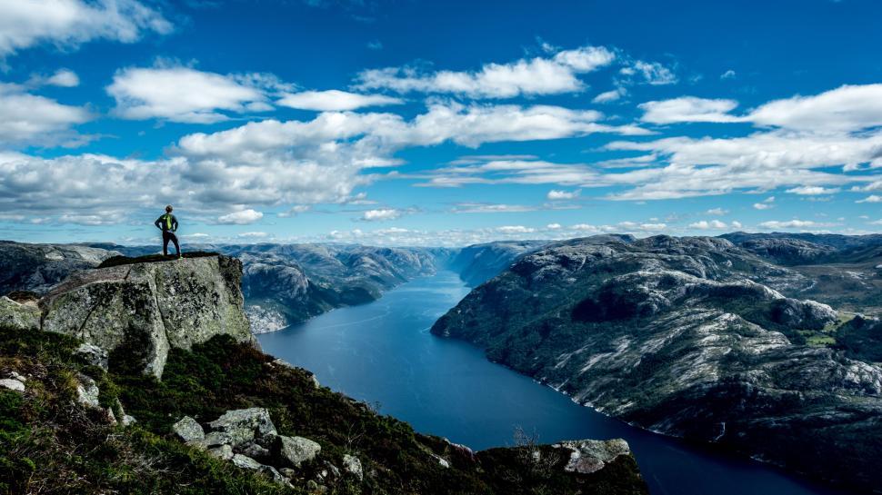 Free Image of Man Standing on Top of a Mountain Near a Lake 