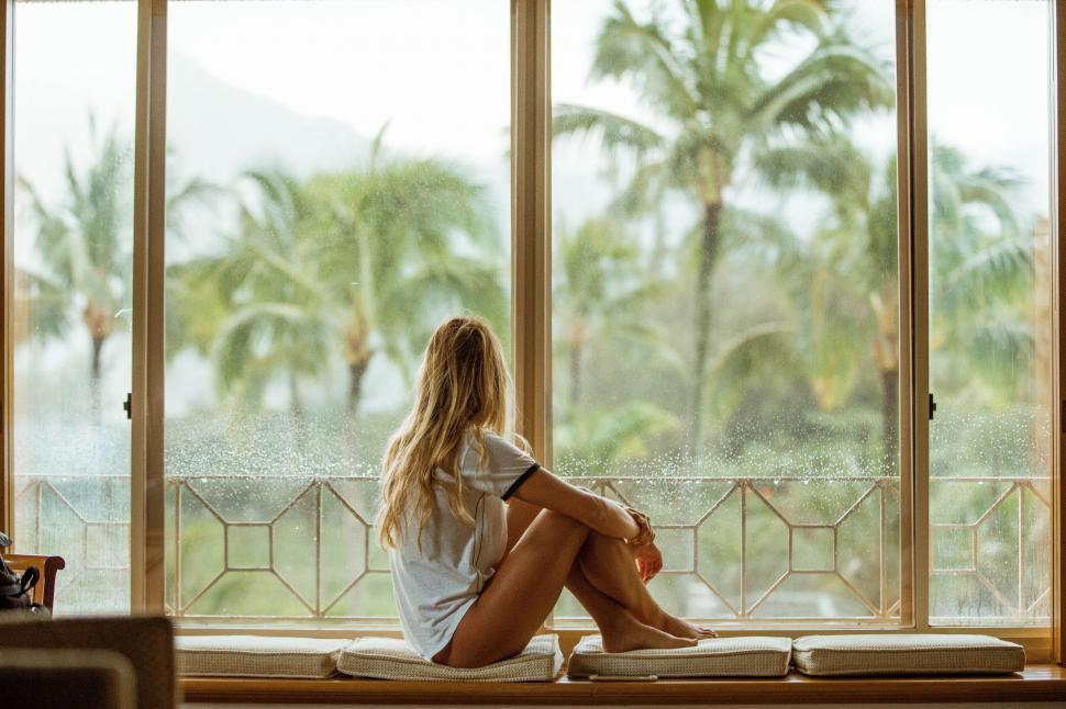 Free Image of Woman Sitting on Window Sill Looking Out 
