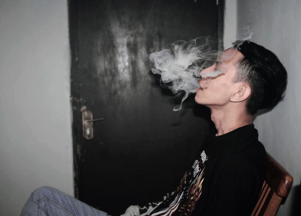 Free Image of Man Sitting in Chair Smoking a Cigarette 