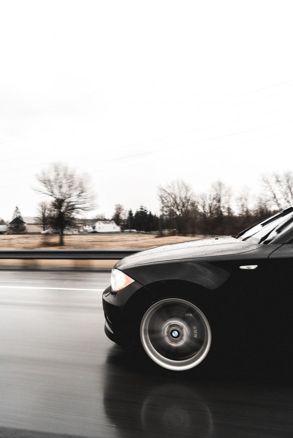 Free Image of Black Car Driving Down Wet Road 