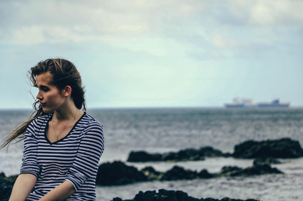 Free Image of Woman Standing on Rocky Beach by Ocean 
