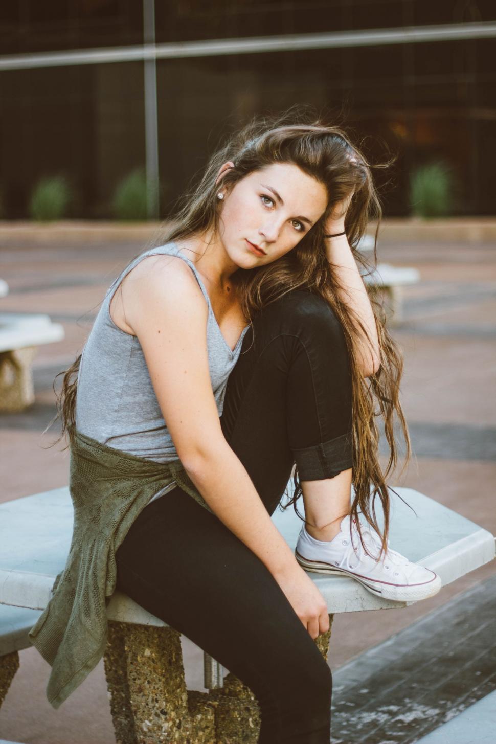 Free Image of Woman Sitting on Bench in Parking Lot 