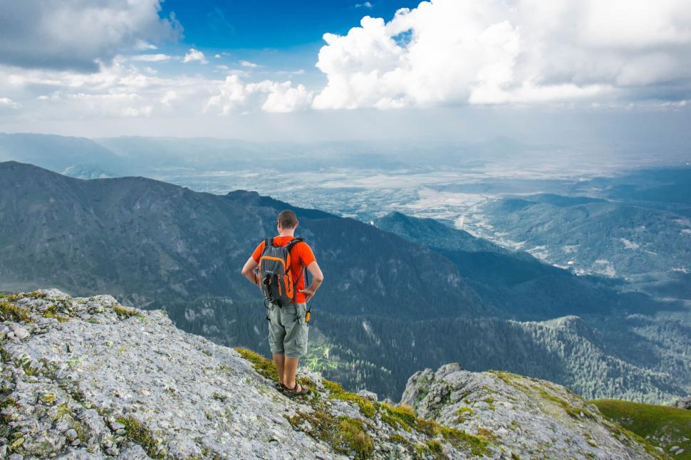 Free Image of Man Standing on Top of a Mountain With a Backpack 