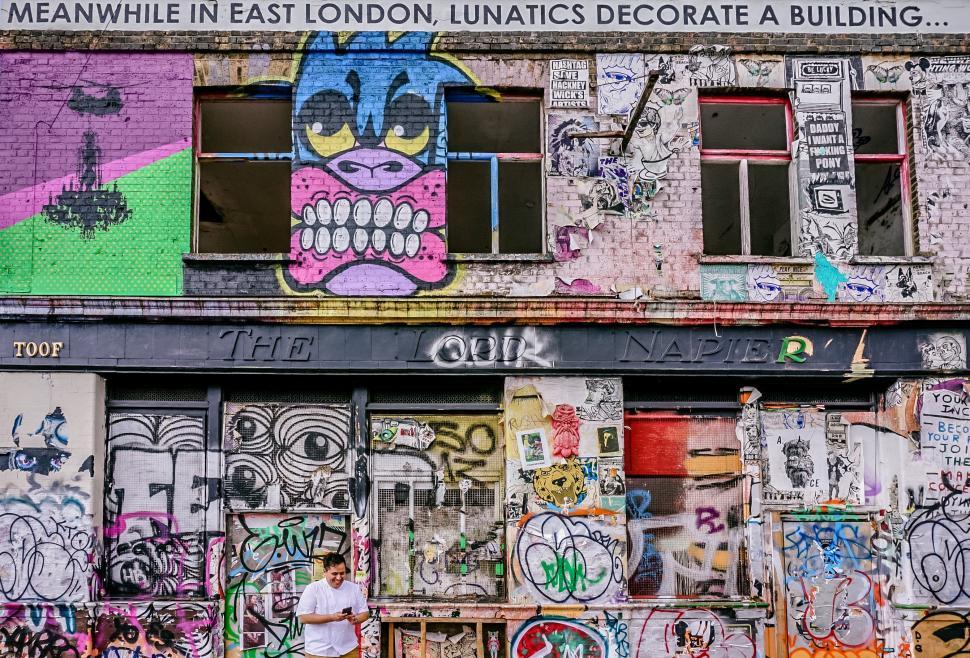 Free Image of Graffiti-Covered Building With Man Standing in Front 