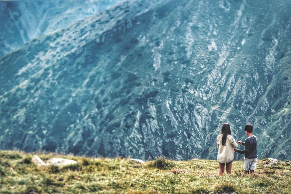 Free Image of Couple Standing on Top of Grass Covered Hillside 