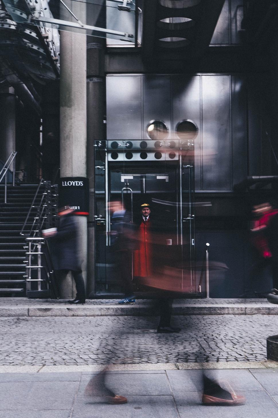 Free Image of Man Walking Down a Street Next to a Tall Building 